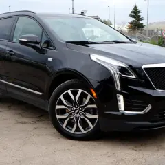 Czarny Cadillac XT5 z chromowanymi detalami i charakterystyczną atrapą chłodnicy stoi na betonowym placu.