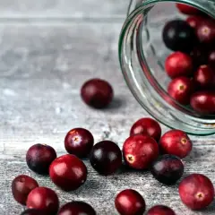 Frische Cranberries, die aus einem Glas rollen. Sie sind eine gesunde Wahl, besonders für Cranberries in der Schwangerschaft.