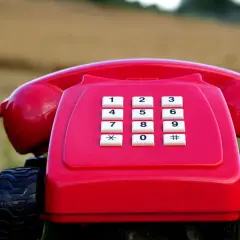 Czerwony telefon stacjonarny na kółkach, jakby gotowy do podróży po najtańszy abonament.