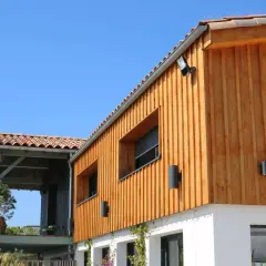 Bardage en bois naturel, un choix idéal pour l'extérieur. La maison moderne arbore des lames de bois clair sous un ciel bleu.