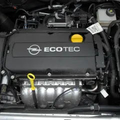 Silnik Ecotec w samochodzie Opel Astra H. Widoczny jest czarny dekiel z logo Opla i napisem Ecotec, żółta miarka oleju oraz elementy układu chłodzenia i dolotowego.