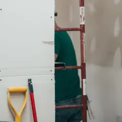 Prace remontowe w toku. Zastanawiasz się, ile schnie gips szybkoschnący? Na budowie widać rusztowanie i narzędzia.