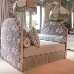 Un cabecero tapizado con flores rosas y azules, bordes a rayas y cojines a juego. Inspiración para como tapizar un cabecero.