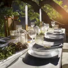 Tavola apparecchiata all'aperto con candele, pigne e rami, evocando un'atmosfera rustica e raffinata, perfetta per una cena nelle cantine di Firenze.