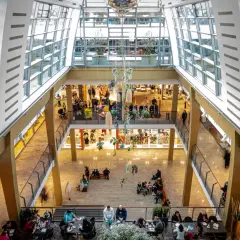 Blick in ein helles Einkaufszentrum in Bergisch Gladbach mit vielen Besuchern, Geschäften und Sitzbereichen.
