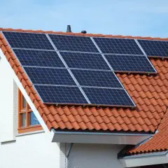 Moderne Solaranlagen auf dem roten Ziegeldach eines Hauses, bereit, Sonnenenergie zu sammeln.