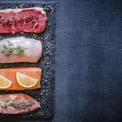 Bœuf, poulet, saumon et porc sur ardoise. Quelle viande contient le plus de protéines ? Le bœuf est en tête.