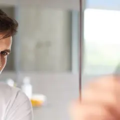 Mężczyzna goli twarz, przygotowując się do nałożenia wody po goleniu lub wody toaletowej.