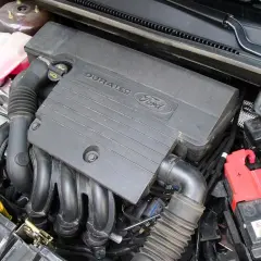 Silnik Duratec w Fordzie Fiesta Mk6. Widoczny jest czarny plastikowy kolektor, przewody i akumulator.