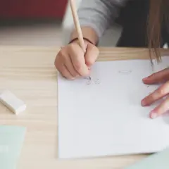 Niño de 12 años practicando caligrafía en un cuaderno. Un lápiz, goma y regla sugieren cómo mejorar la letra de un niño de 12 años.