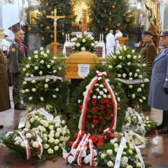 Trumna w otoczeniu wieńców, żołnierze w mundurach stoją na straży.