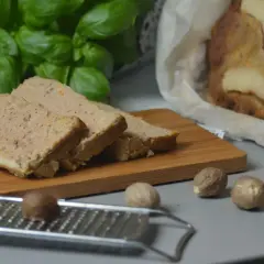Krojony pasztet z królika, pachnący jak babciny przepis, na desce z gałką muszkatołową i świeżą bazylią.