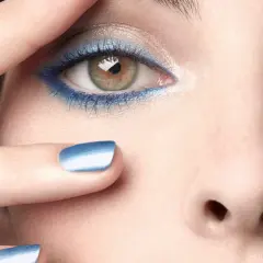Occhi con ombretto blu elettrico e unghie abbinate, un tocco di **chanel cipria** per un look audace.