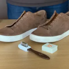 Paire de baskets en cuir marron clair, brosse et gomme pour apprendre comment nettoyer des chaussures en cuir marron clair.