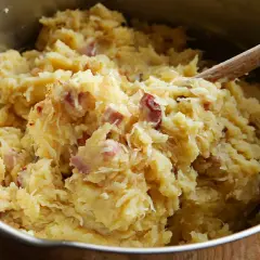 Panczkraut w garnku, gotowy do podania. Drewniana łyżka miesza ziemniaczaną masę z kawałkami boczku.