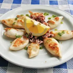 Chipirones a la plancha, tiernos y dorados, servidos con limón y un toque de perejil picado. Un plato sencillo y delicioso.