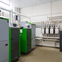 Nowoczesna kotłownia gazowa, gdzie spełnione są wszystkie warunki techniczne. Widać tu kilka kotłów, rury z izolacją i manometry.