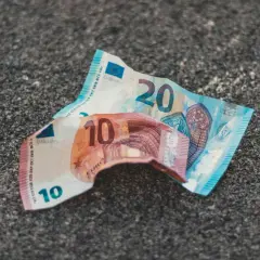Uszkodzone banknoty 10 i 20 euro leżą na szarej powierzchni. Dowiedz się, gdzie wymienić uszkodzony banknot euro.