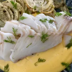 Vit fisk serveras med krämig sås och ugnsbakad fänkål, garnerad med dill.