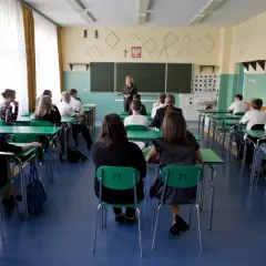 Lekcja w polskim gimnazjum, kiedy weszły gimnazja w polsce. Uczniowie siedzą w ławkach, nauczycielka stoi przy tablicy.