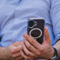 Mężczyzna w niebieskiej koszuli trzyma telefon z okrągłym wzorem. Czuć w tym nowoczesną haptykę.