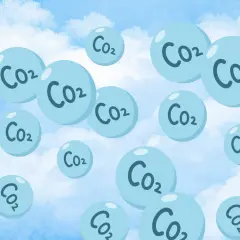 Niebieskie bańki z napisem CO2 unoszące się na tle błękitnego nieba z chmurami.