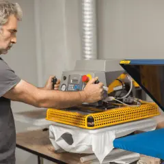 Un homme ajuste une presse à chaud pour le flocage sur polyester, contrôlant la température pour un transfert parfait.