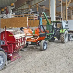 Holzspalter und Traktor mit Anhänger, bereit für den Transport. Die mobilen Förderbänder sind im Einsatz, um das Holz zu bewegen.