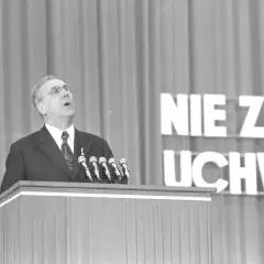 Edward Gierek przemawia na tle napisu "NIE ZAW". Ciekawostki z jego czasów często dotyczą przemówień i wystąpień publicznych.