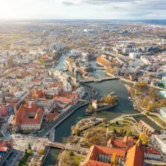 Widok z lotu ptaka na Wrocław z Odrą i licznymi mostami. Widać zabytkowe kamienice i nowoczesne budynki, idealne miejsca na mieszkania na sprzedaż Wrocław.