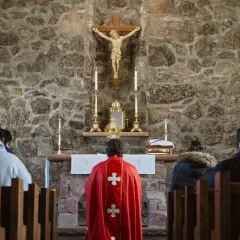 Ludzie w kościele, przed ołtarzem z krzyżem i monstrancją.