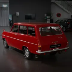 Röd Opel Kadett Caravan, en klassiker som kan vara en skattebefriad bil. Bredvid står en blå bil och en racingbil.