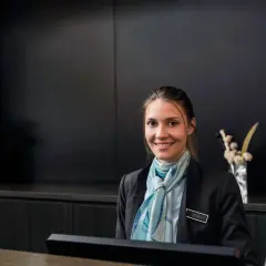 Lächelnde Hotelfachfrau mit Schal, bereit für ihre Weiterbildung.