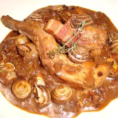 Guiso de conejo con caracoles, bañado en una rica salsa oscura, con trozos de tocino y una ramita de romero.