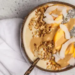 Cremige Chia Overnight Oats im Kokosnussschalen-Bowl mit Pfirsich, Granola und Erdnussbutter. Ein gesunder Start in den Tag!