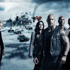 Die Hauptdarsteller der besetzung von Fast & Furious 8 stehen vor einer eisigen Landschaft mit explodierenden Fahrzeugen und einem Helikopter.