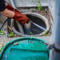 Un professionnel utilise un jet d'eau puissant pour le nettoyage du tuyau d'évacuation, délogeant les obstructions.