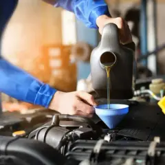 Mechanik wlewa olej do silnika. Dowiedz się, ile za wymianę oleju i filtrów w samochodzie.