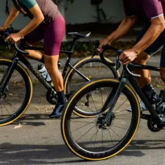 Two cyclists on road bikes, one with a blue book in their jersey pocket, showcase the value of a high-performance bike.