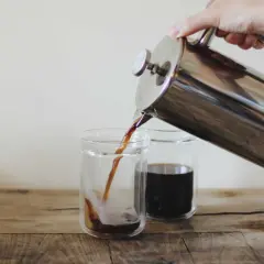 Versando caffè americano da una french press in due bicchieri. Le dosi caffè americano sono perfette per iniziare la giornata.