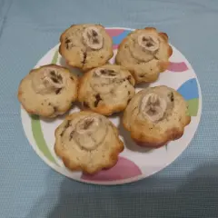 Sei muffin banana e cioccolato, guarniti con una fetta di banana, su un piatto colorato.