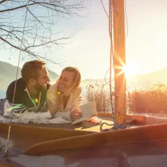 Glückliches Paar auf einem Boot bei Sonnenuntergang. Ihre christliche Partnersuche Erfahrungen haben sie hierher geführt.