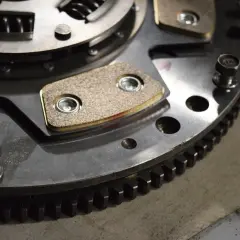 Metalowe elementy sprzęgła w automacie, z widocznymi okładzinami ciernymi i zębatym wieńcem.