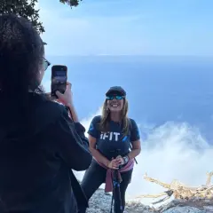 Två kvinnor njuter av en fantastisk vandring på Mallorca. En tar foto av den andra med havet och molnen i bakgrunden.
