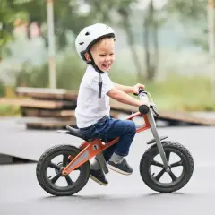Uśmiechnięty chłopiec w kasku radośnie jeździ na rowerku biegowym. Od kiedy ma rowerek, świat jest pełen przygód!