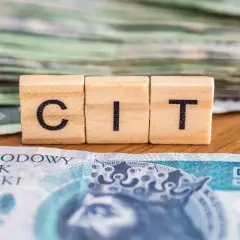Drewniane klocki z literami "CIT" na tle polskich banknotów. Kluczowe dla dokumentacji cen transferowych.