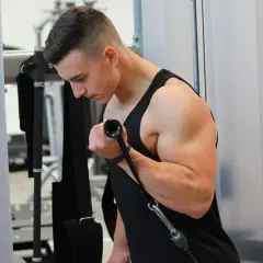 Ein Mann trainiert im Fitnessstudio und baut beeindruckende Muskeln am Oberarm auf.
