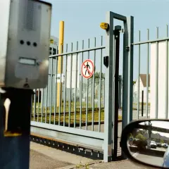 Solidna konstrukcja bramy przesuwnej z domofonem i znakiem zakazu ruchu pieszego.