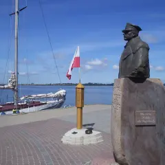 Pomnik upamiętniający zaślubiny Polski z morzem. Obok żaglowiec i polska flaga.