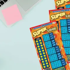 Trzy zdrapki Super Linie leżą obok telefonu i słuchawek. Dowiedz się, jak odczytać zdrapkę Super Linie, aby wygrać 75 000 zł!
